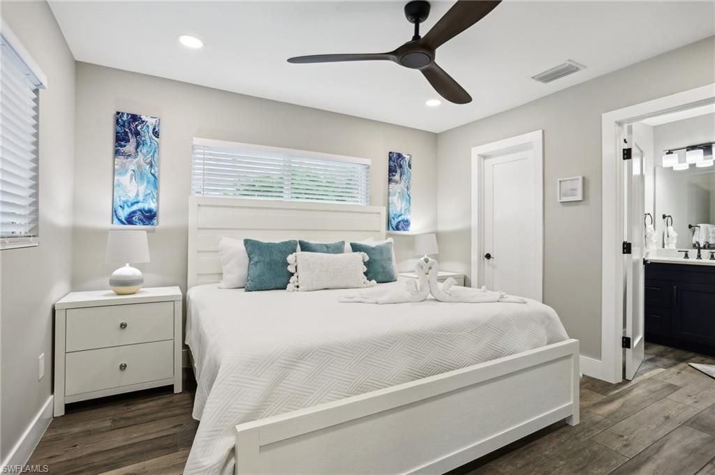 Bedroom with dark hardwood / wood-style floors, connected bathroom, sink, and ceiling fan