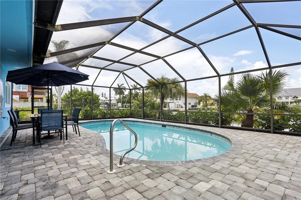 View of pool featuring a patio and glass enclosure
