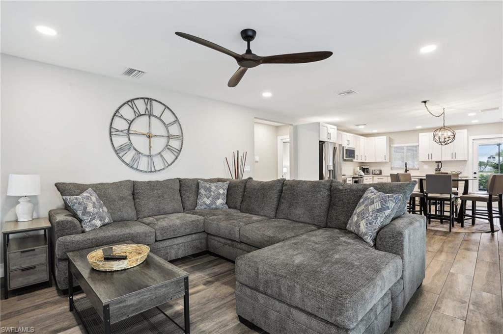 Living room featuring wood-type flooring and ceiling fan with notable chandelier
