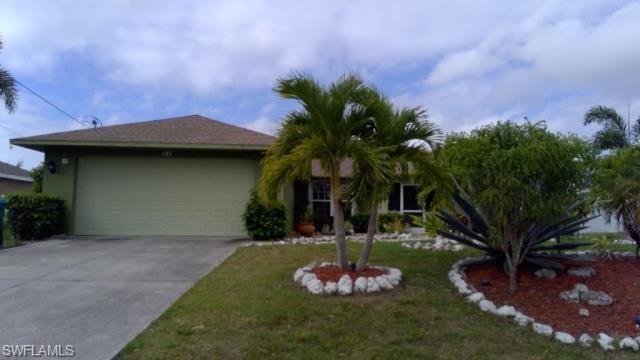 Single story home with a garage and a front lawn