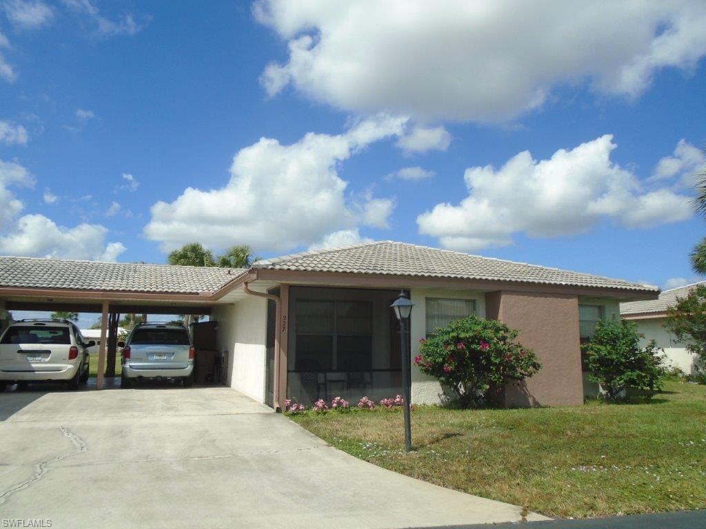View of front of property with a carport and a front yard