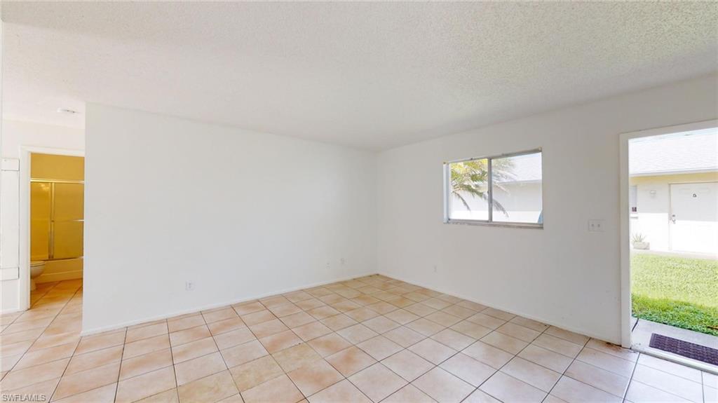 Empty room with a textured ceiling and light tile patterned floors