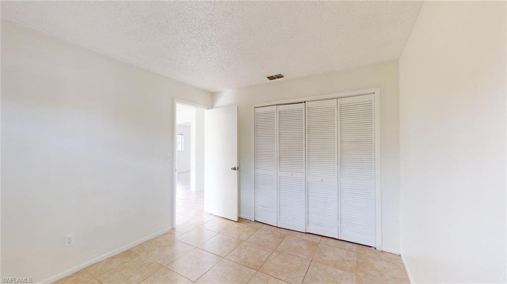 Unfurnished bedroom featuring light tile patterned flooring, a closet, and a textured ceiling