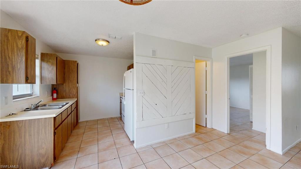 Kitchen with light tile patterned flooring, sink, and white fridge