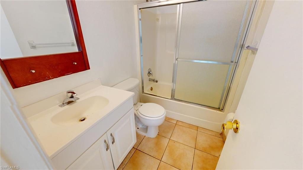 Full bathroom featuring vanity, tile patterned floors, combined bath / shower with glass door, and toilet