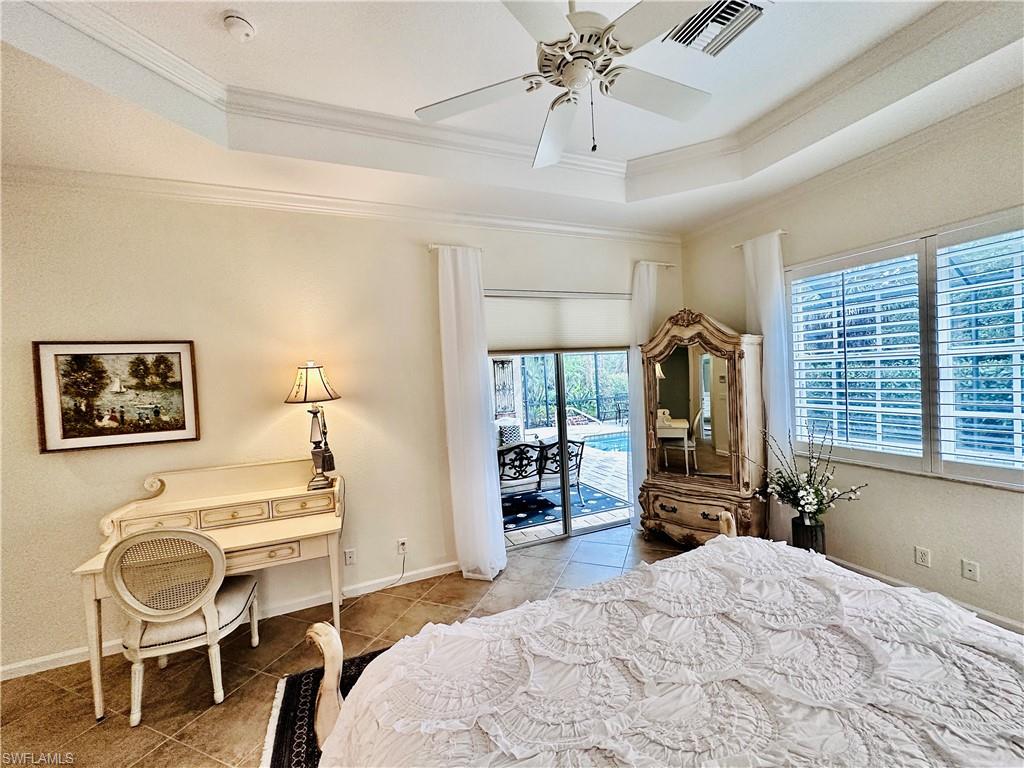 Bedroom with a raised ceiling, access to outside, light tile patterned floors, and ceiling fan