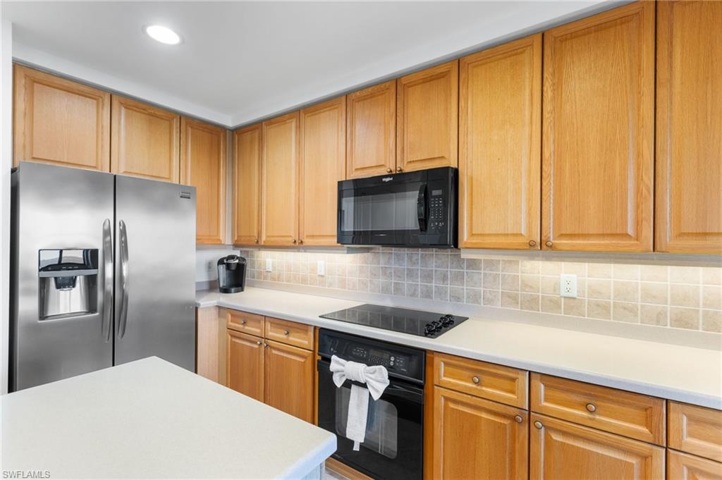 Honey colored wood cabinets and tumbled marble backsplash and underlighting.