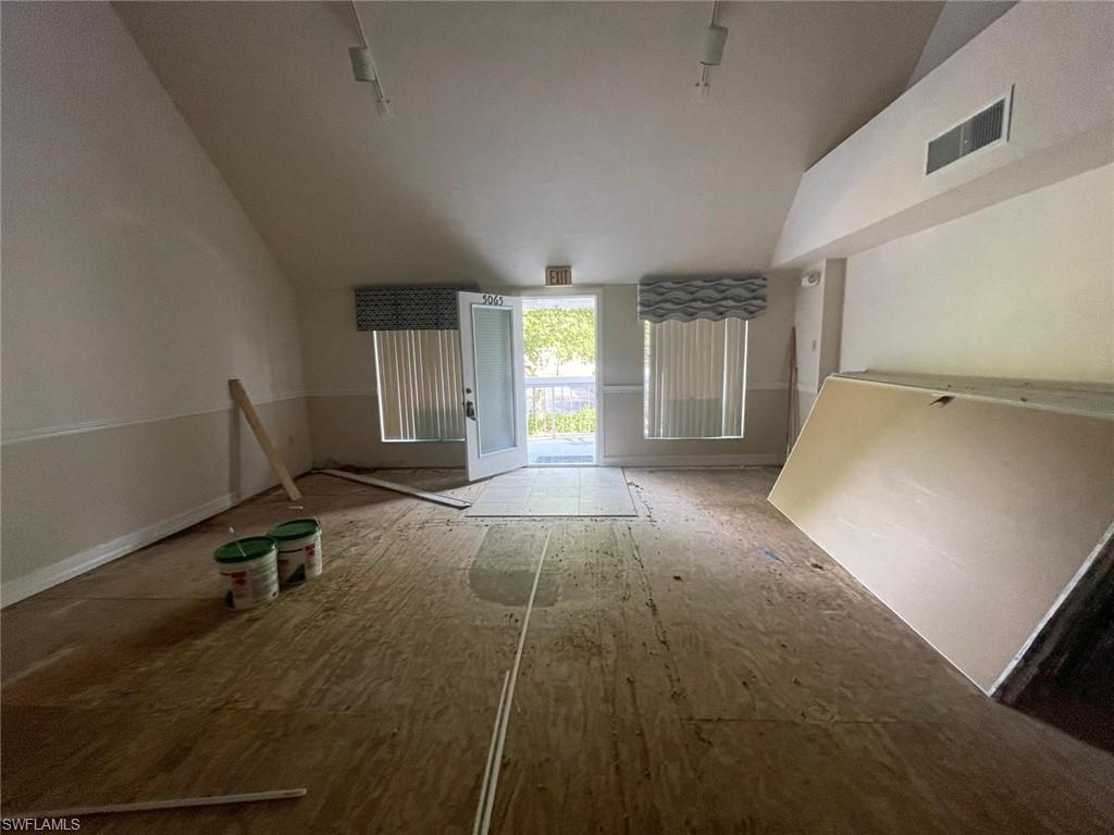 Unfurnished living room with dark wood-type flooring and vaulted ceiling