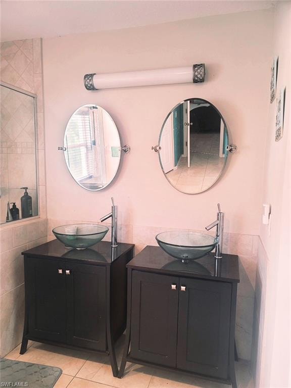 Bathroom with tile walls, dual vanity, and tile patterned flooring
