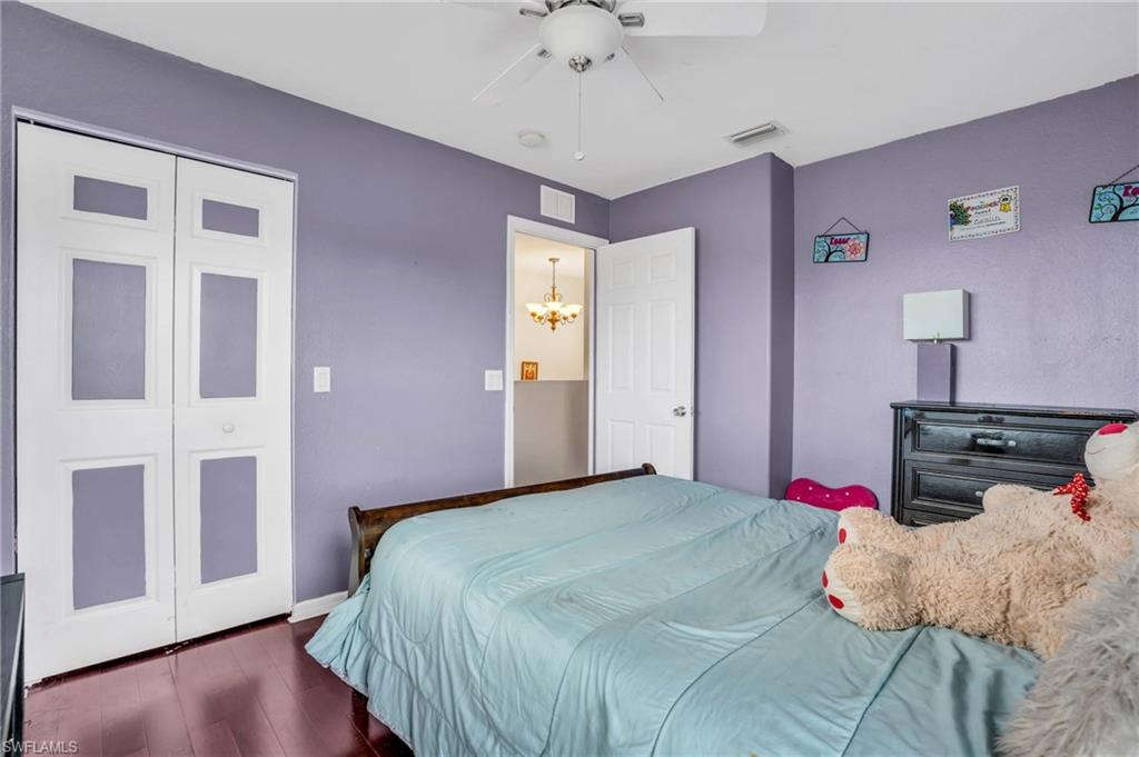 Bedroom with ceiling fan with notable chandelier, a closet, and dark hardwood / wood-style floors