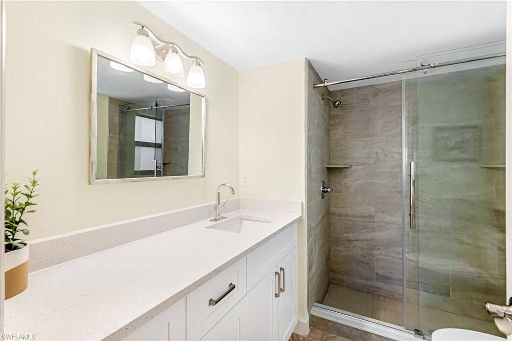 Bathroom with toilet, an enclosed shower, and vanity