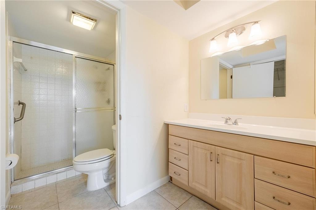 Primary bathroom featuring tile patterned flooring, vanity, toilet, and a shower with shower door