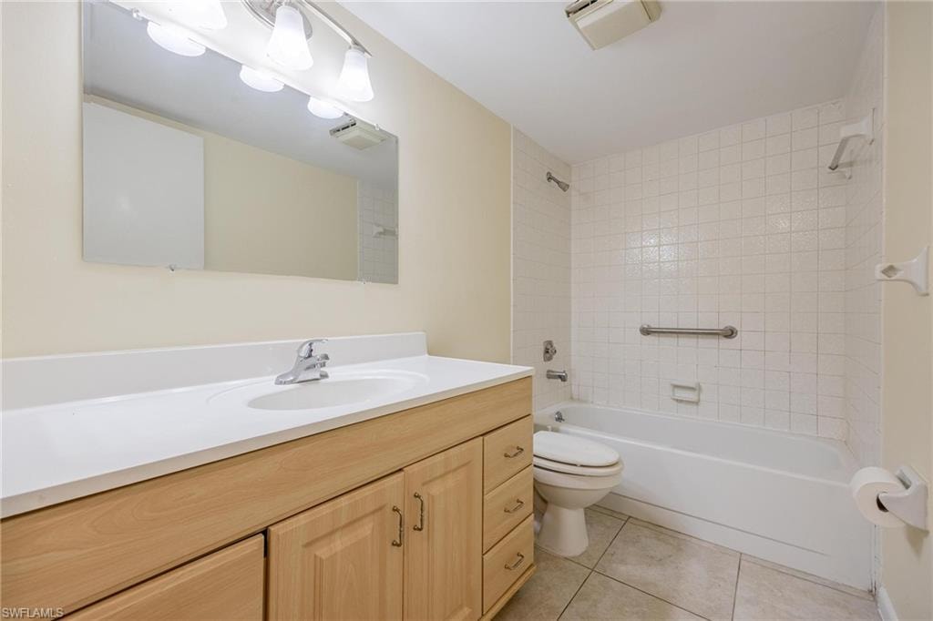 Full bathroom with vanity, tiled shower / bath combo, toilet, and tile patterned floors