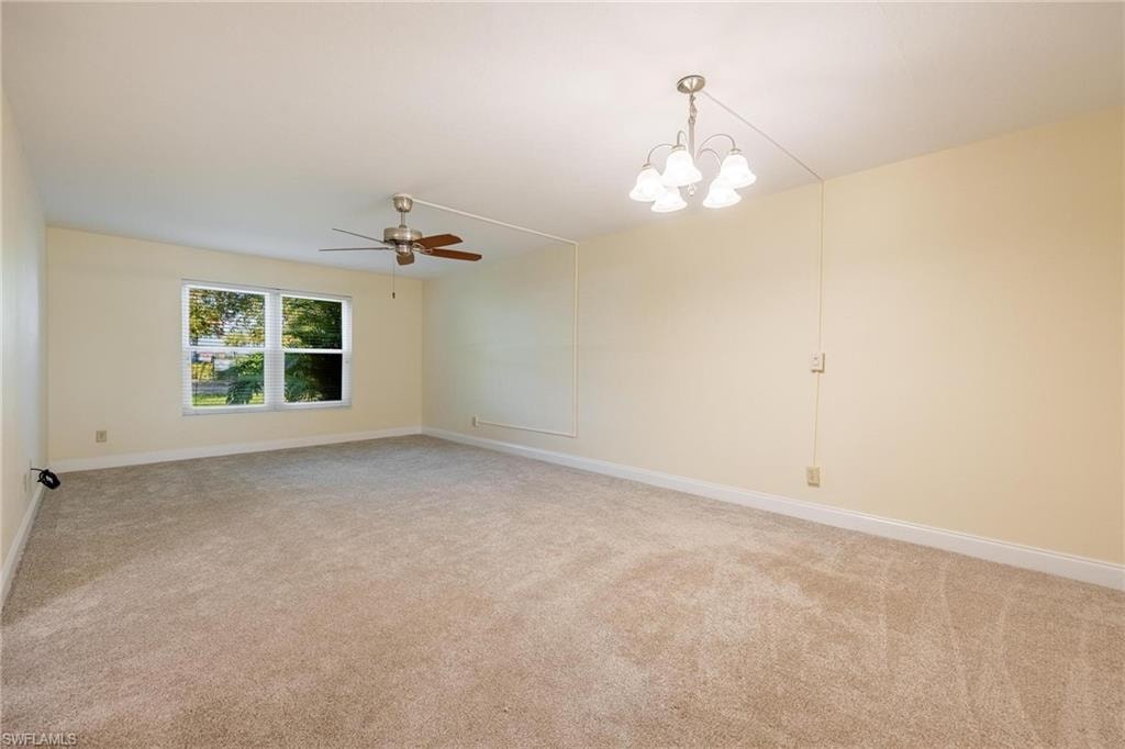 Living room featuring ceiling fan with notable chandelier and carpet