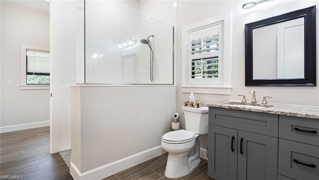 Bathroom with toilet, tile walk-in shower, and vanity