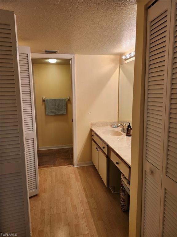 Bathroom featuring a textured ceiling, vanity, and wood-type flooring