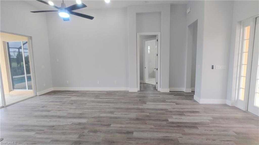 Spare room with a wealth of natural light, high vaulted ceiling, ceiling fan, and light wood-type flooring
