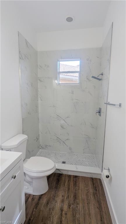 Bathroom with vanity, toilet, wood-type flooring, and a tile shower