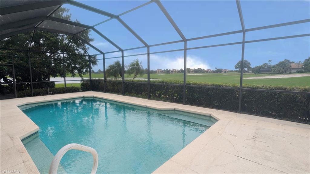 View of pool featuring glass enclosure and a patio