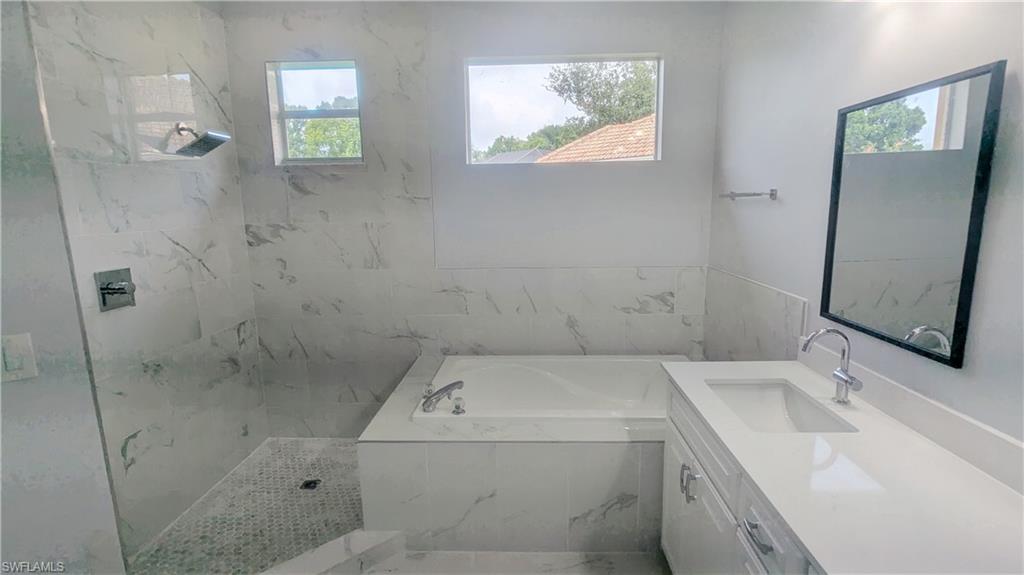 Bathroom with independent shower and bath, a wealth of natural light, and vanity