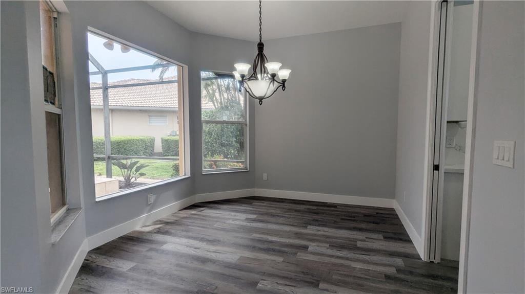 Unfurnished dining area featuring dark wood-type flooring and an inviting chandelier