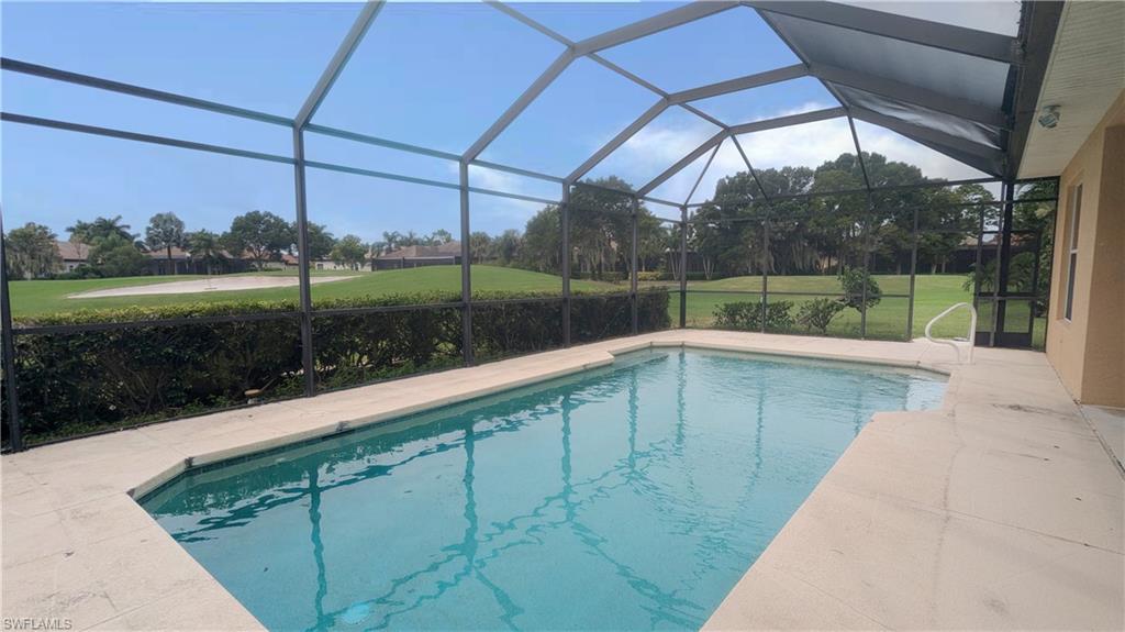 View of pool with a yard and glass enclosure