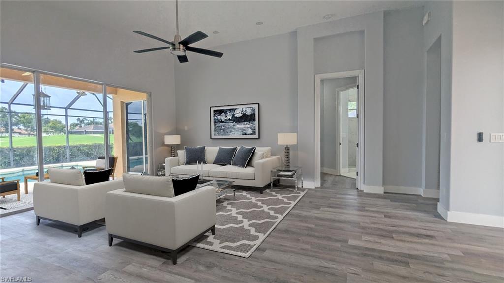 Living room featuring a healthy amount of sunlight, high vaulted ceiling, hardwood / wood-style flooring, and ceiling fan