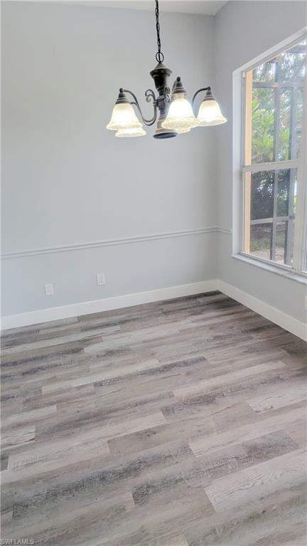 Unfurnished room with hardwood / wood-style floors and a chandelier