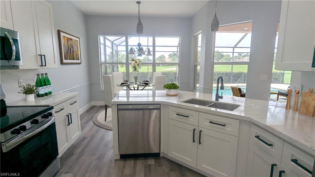 Kitchen with white cabinets, stainless steel appliances, sink, and a healthy amount of sunlight