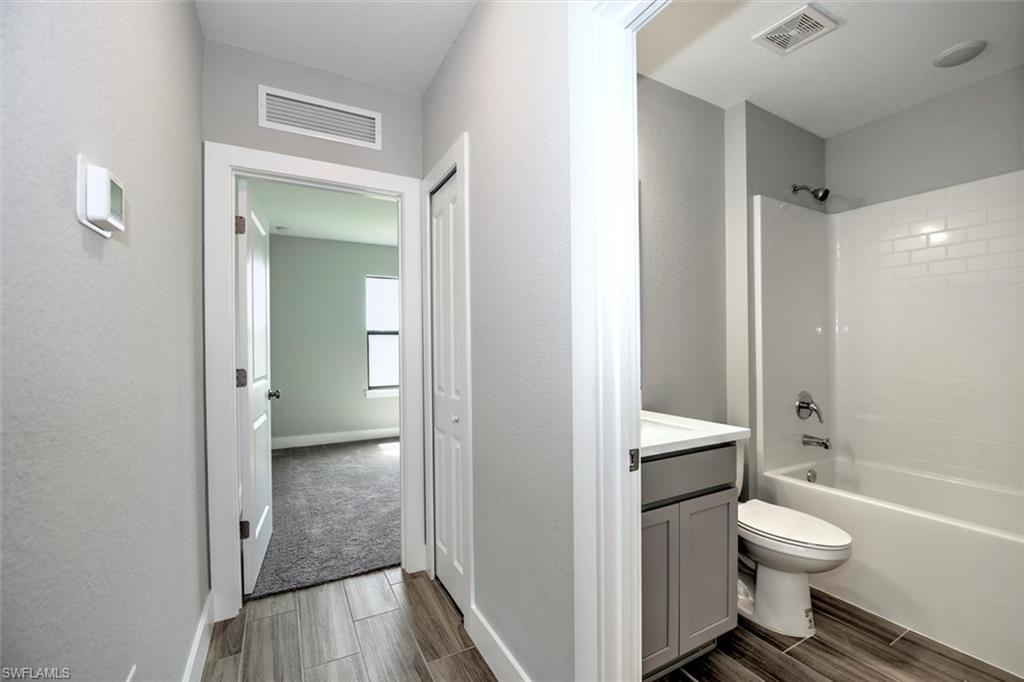 Full bathroom with tiled shower / bath, vanity, toilet, and hardwood / wood-style flooring