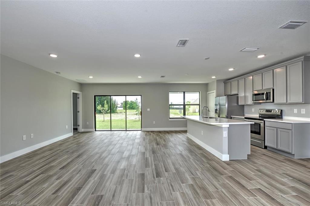 Kitchen with appliances with stainless steel finishes, sink, gray cabinetry, and light hardwood / wood-style floors