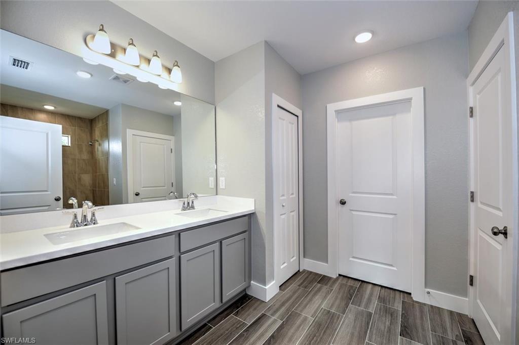 Bathroom with hardwood / wood-style floors, tiled shower, and vanity