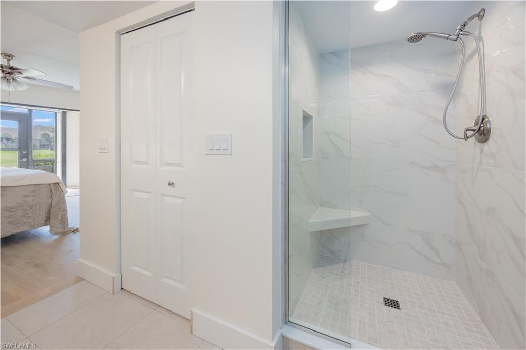 Bathroom featuring ceiling fan, hardwood / wood-style flooring, a tile shower, and french doors