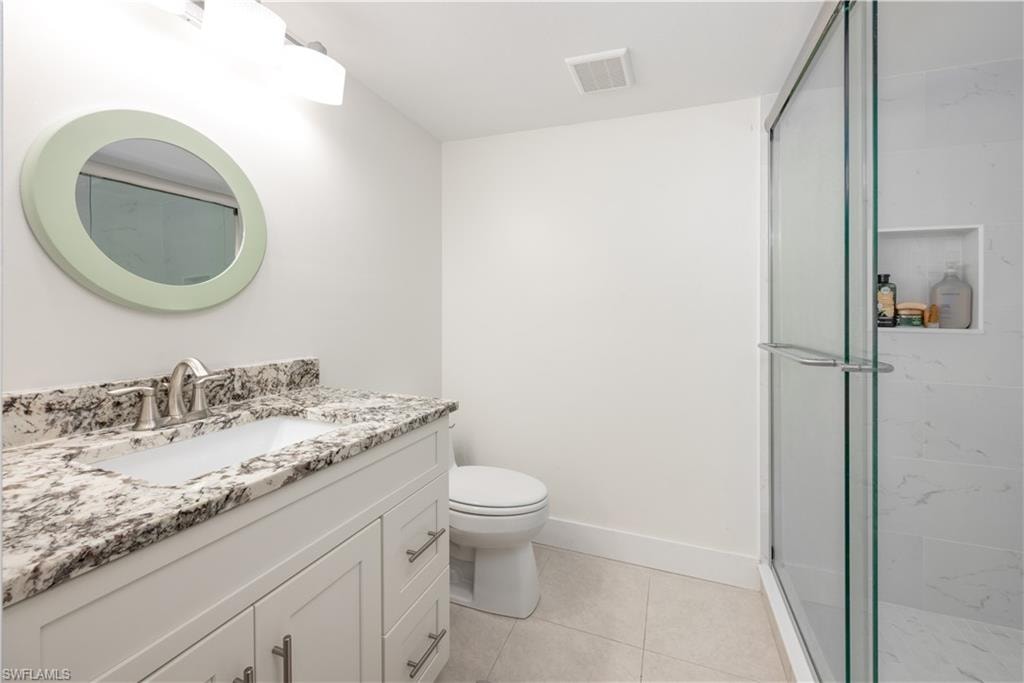 Bathroom featuring vanity, toilet, tile patterned flooring, and a shower with door