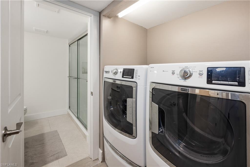 Laundry room with washer and clothes dryer and light tile patterned flooring