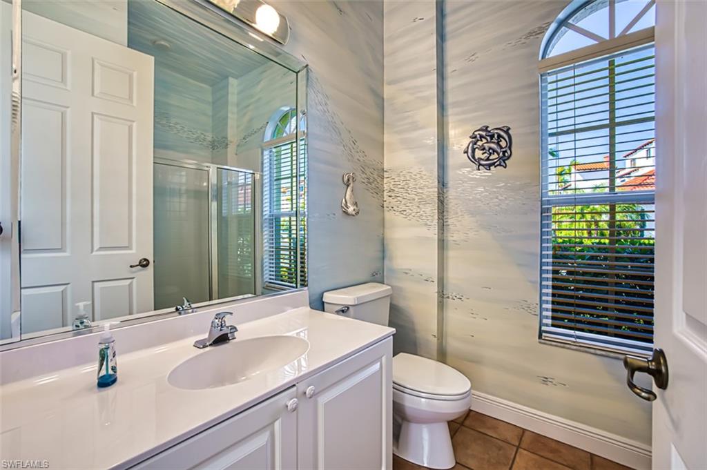 Bathroom with an enclosed shower, vanity, toilet, and tile patterned floors