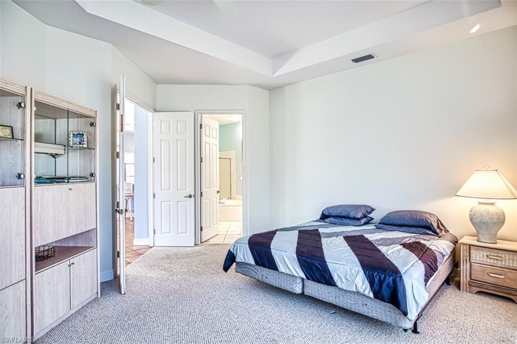 Carpeted bedroom featuring a raised ceiling and ensuite bath