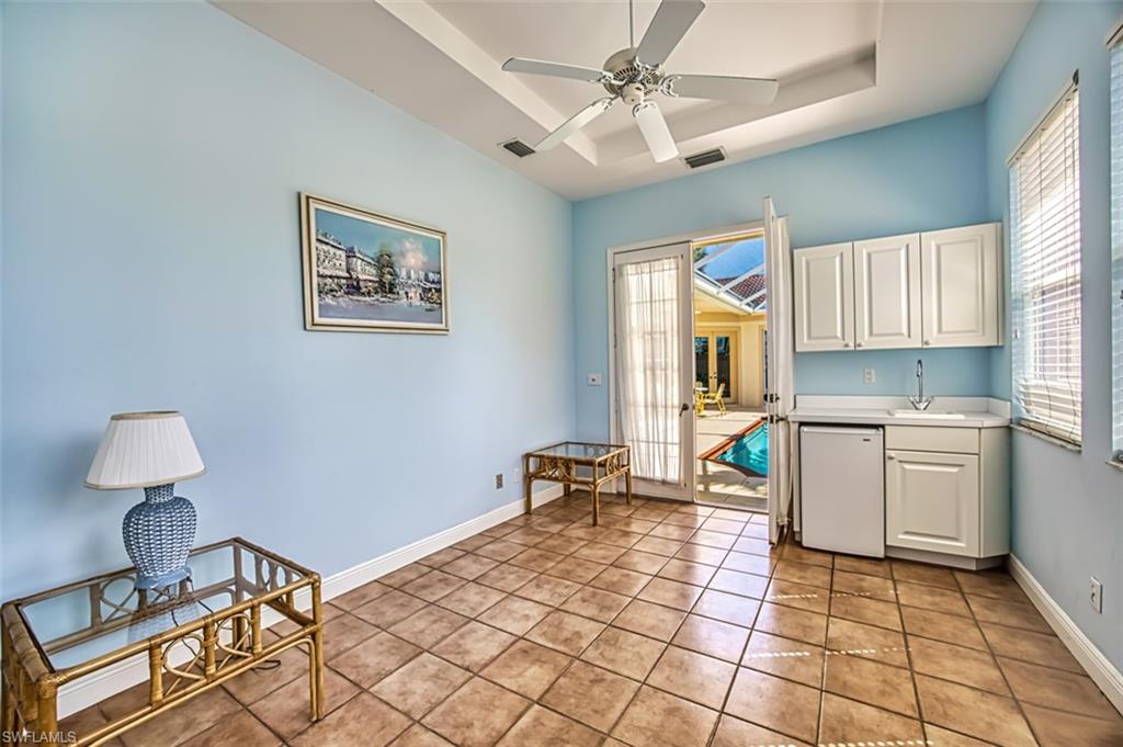 Living area with a raised ceiling, ceiling fan, sink, and light tile patterned floors