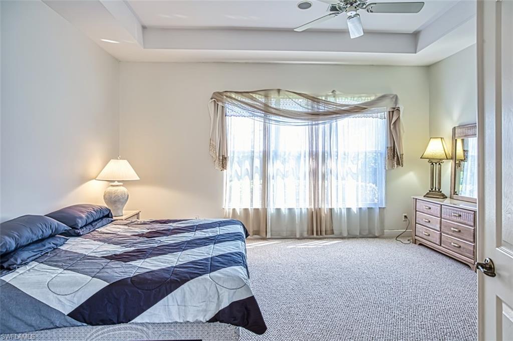 Bedroom featuring a tray ceiling, ceiling fan, and carpet floors