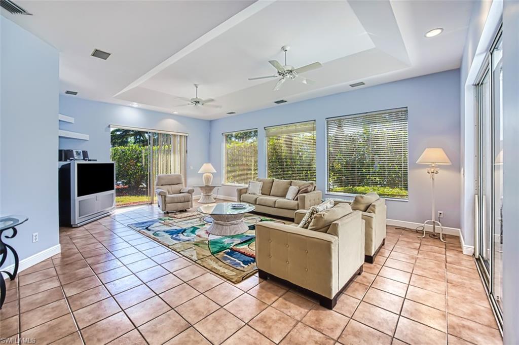 Tiled living room with ceiling fan and a raised ceiling