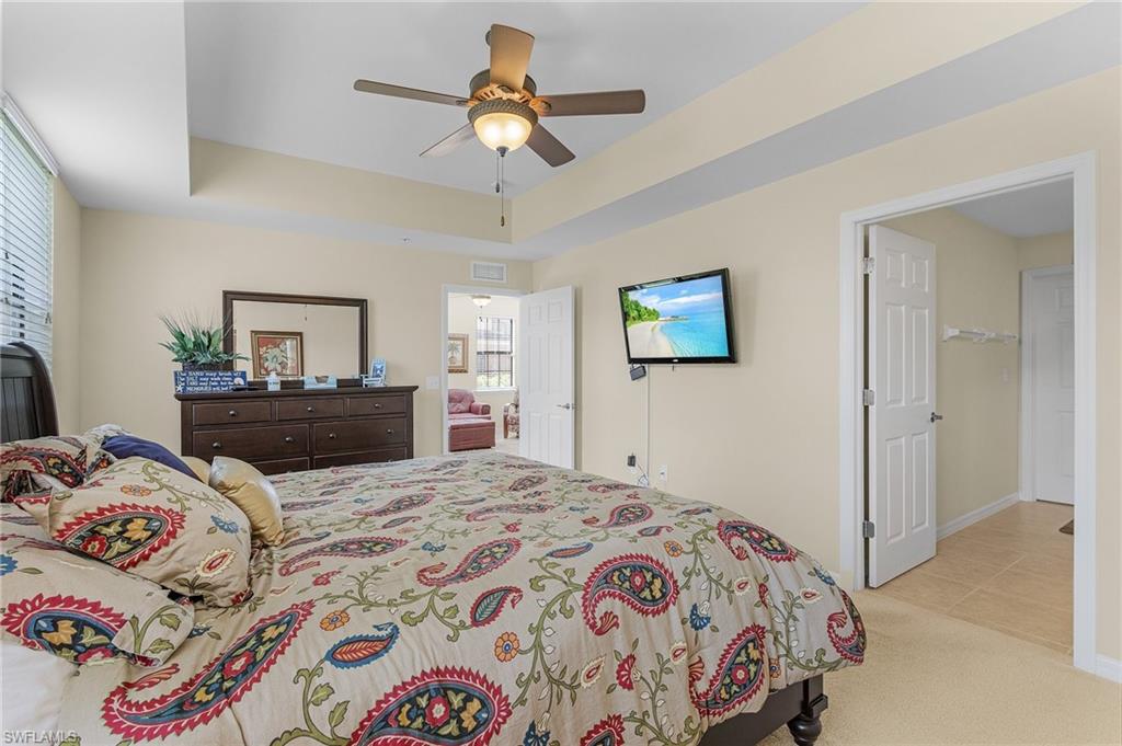 Carpeted bedroom featuring a tray ceiling and ceiling fan