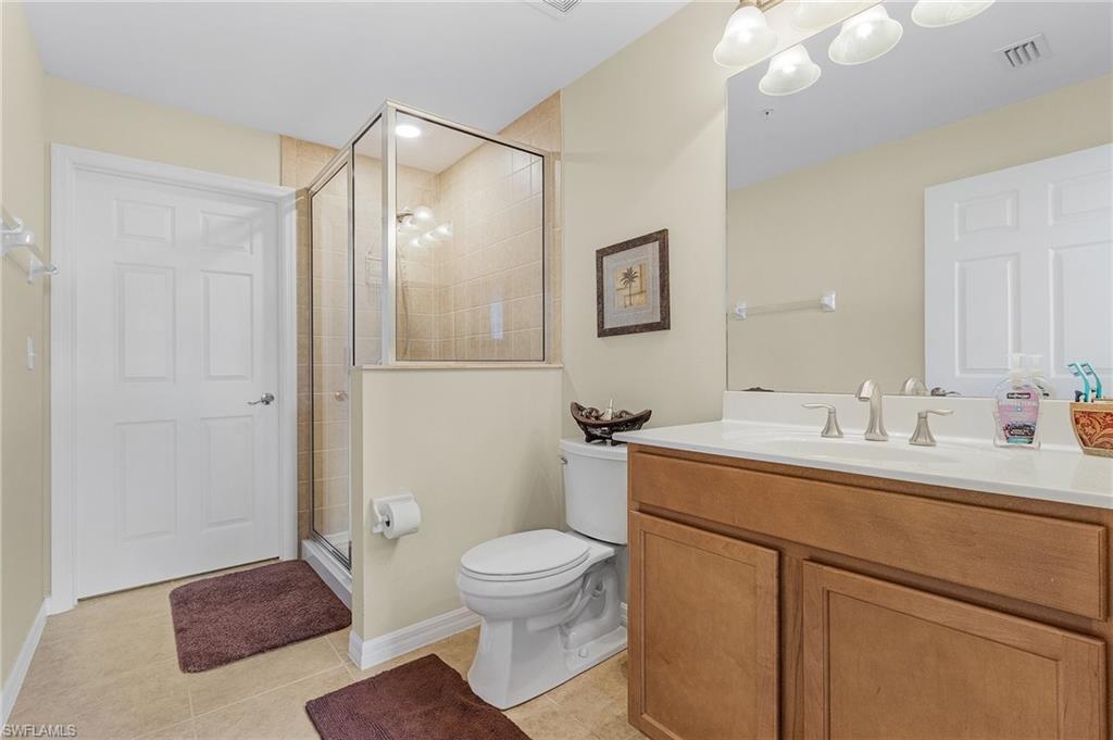 Bathroom featuring tile patterned floors, vanity, toilet, and a shower with shower door