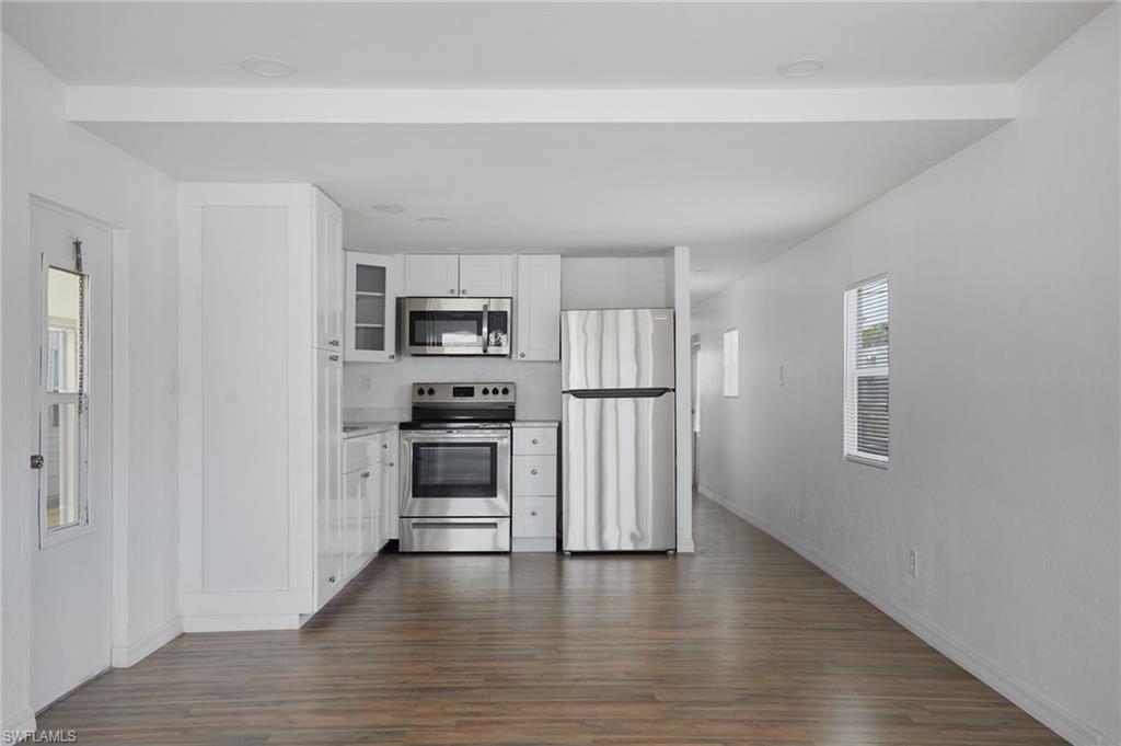 Kitchen with white cabinetry, baseboards, appliances with stainless steel finishes, and dark wood-type flooring