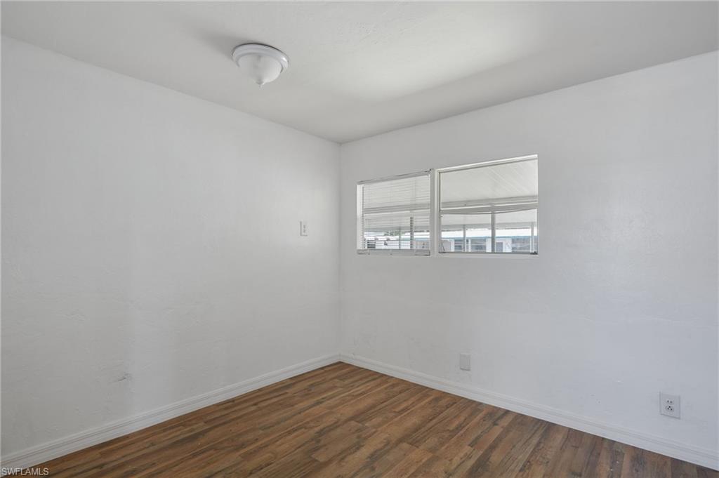 Unfurnished room featuring baseboards and dark wood-type flooring