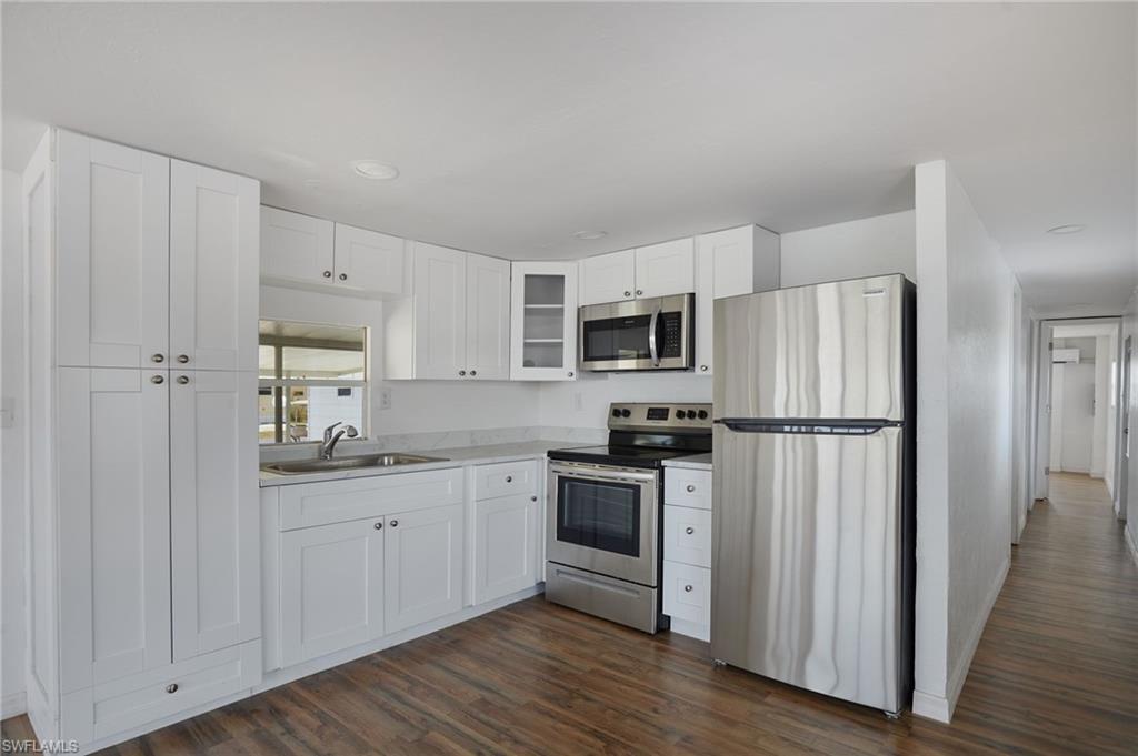 Kitchen with light countertops, stainless steel appliances, dark wood-style floors, and a sink