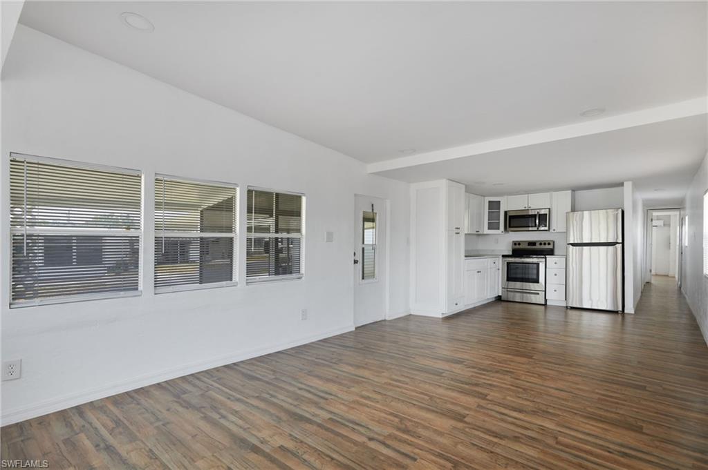 Unfurnished living room with baseboards and dark wood-type flooring