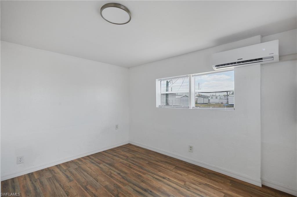Empty room with baseboards, a wall mounted AC, and wood finished floors