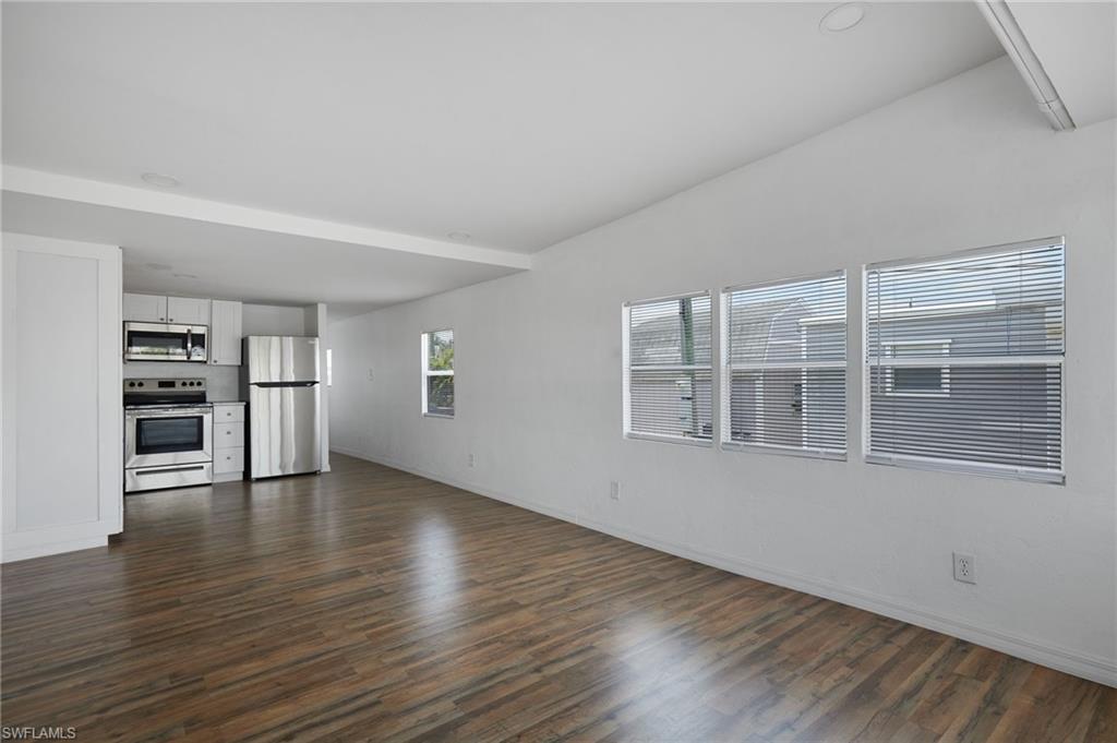 Unfurnished living room with baseboards and dark wood-style floors