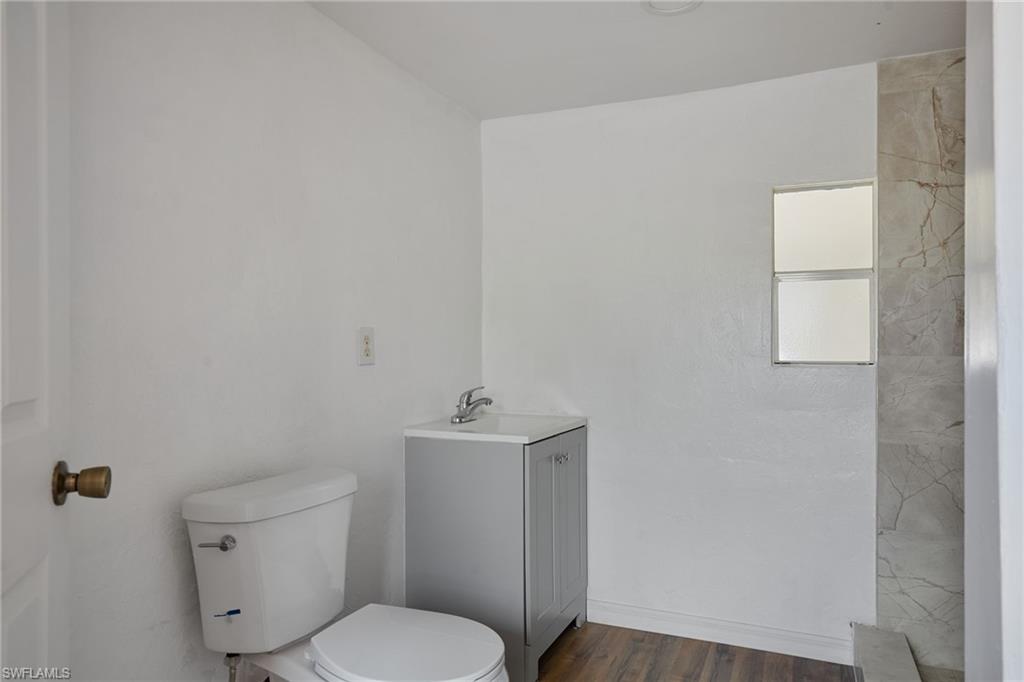 Full bath with vanity, wood finished floors, and toilet