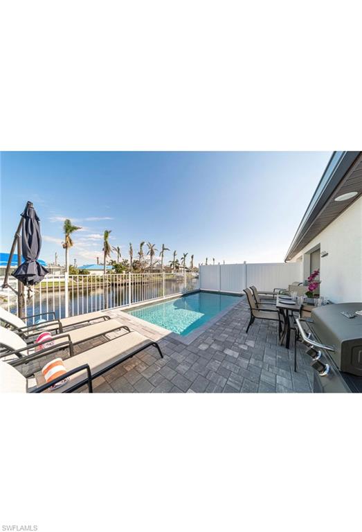 View of pool with a water view, a patio, and area for grilling